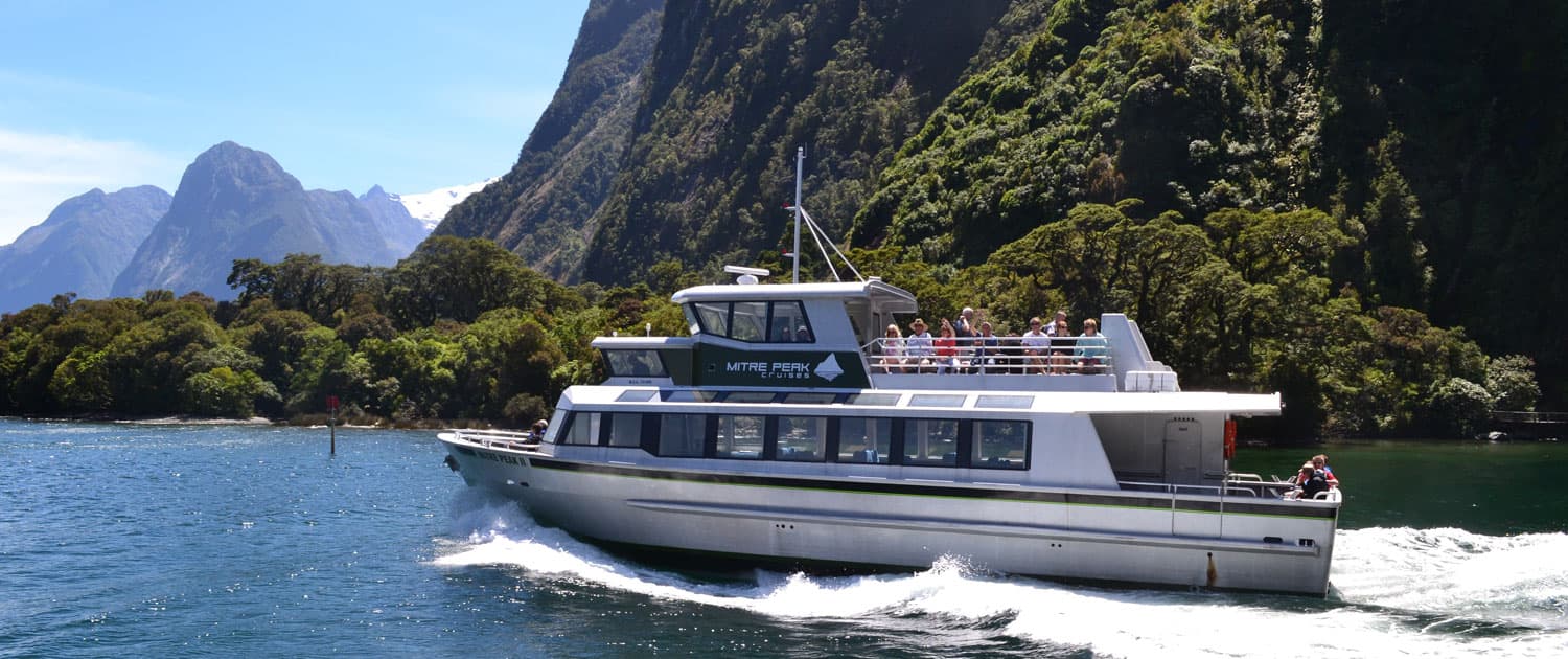 People seated on the top deck of the boat during a Milford Sound nature cruise