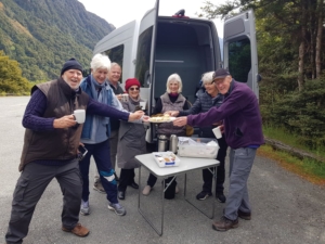 A small group having a cup of tea and biscuit at one of the many nature stops on the way to Milford Sound