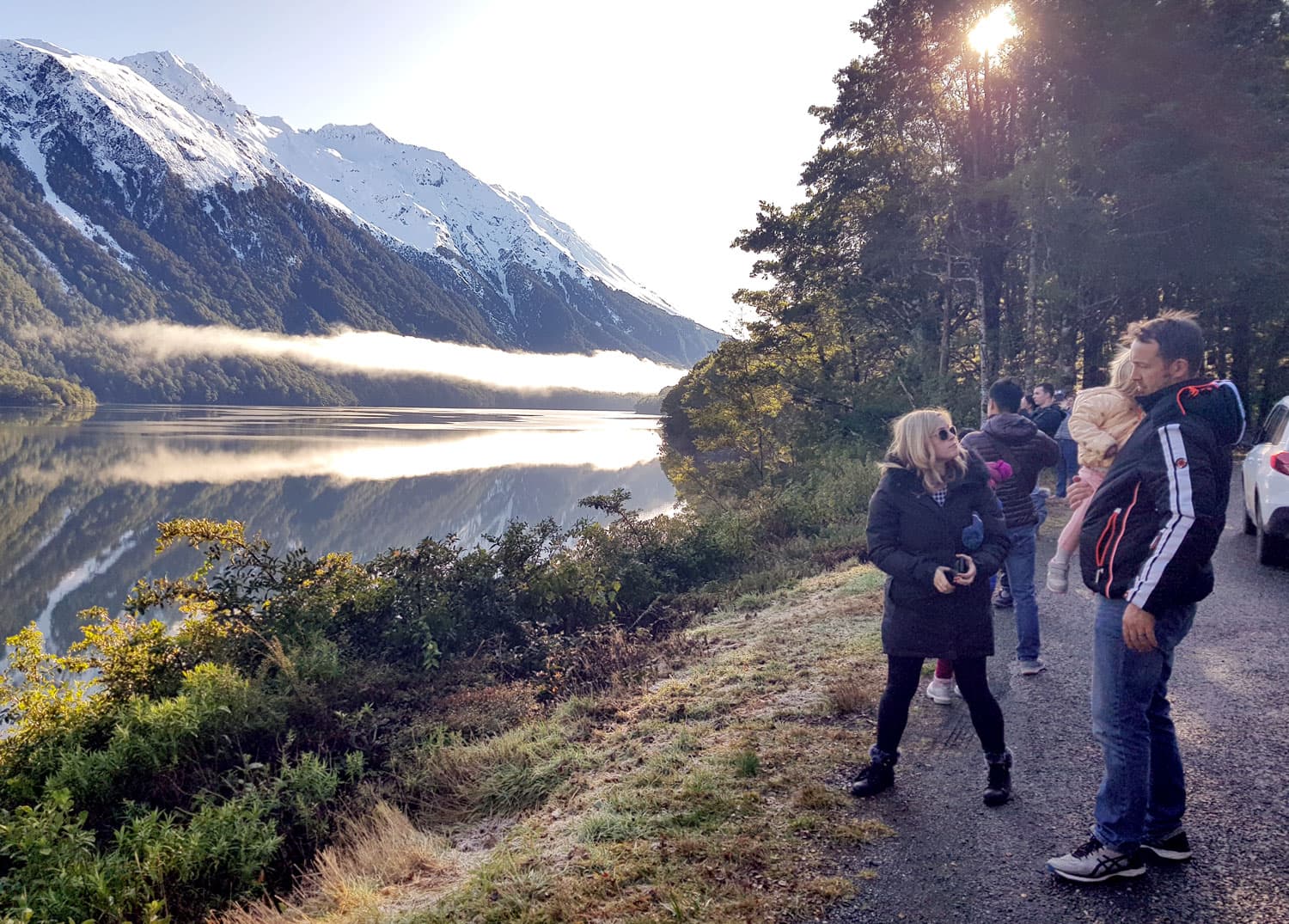 Family group viewing the stunning Lake Te Anau and snow-capped mountains